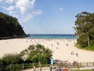 Vistas panorámicas de la Playa La Franca en Asturias , de arena blanca, con un cielo azul y turistas tomando el sol y disfrutando en el verano de 2020