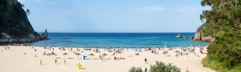 Vistas de la Playa La Franca en Asturias , de arena blanca, con un cielo azul y turistas tomando el sol y disfrutando en el verano de 2020