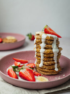 Plate with a row of banana pancakes and a few pieces of strawberries