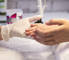 Examination and disinfection of the client's hands by a manicure master in a beauty salon before the manicure procedure and strengthening the nails with gel. The concept of professional nail and hand 