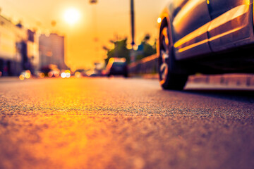 Sunset in the city, the headlights of the approaching cars. Close up view from the asphalt level