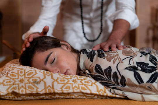 Male spiritual therapist rubbing hands and touching relaxed female head with back during alternative therapy
