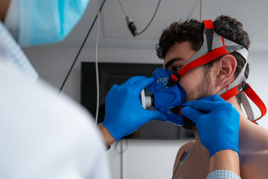 Unrecognizable medic putting on mask on face of patient while preparing for cardiac stress test in modern hospital