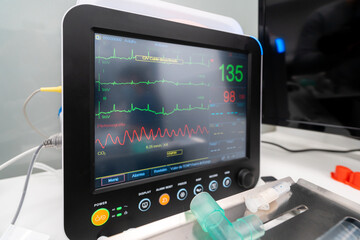 Professional medical device showing heart rate graphs and numbers on display on table in clinic