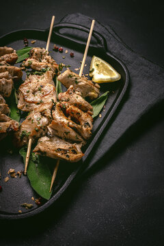From above of appetizing freshly cooked meat on skewers served on tray on black table