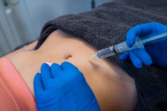 From above of crop anonymous professional beautician making injection for woman during cellulite treatment in beauty clinic