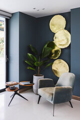 Vertical shot of a modern house with a big plant next to small round tables and comfortable chair