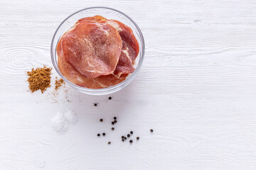 dried meat and a piece of fresh pork with spices on a light background. top view
