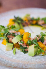 Vertical shot of delicious salmon tartare meal with peppers and leaves