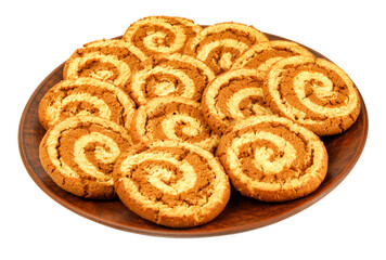 A beautiful cookie with a spiral pattern on a clay plate is isolated on a white background.