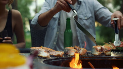 Fototapeta premium Unknown guy preparing bbq fish outside. Man chef finishing cooking process