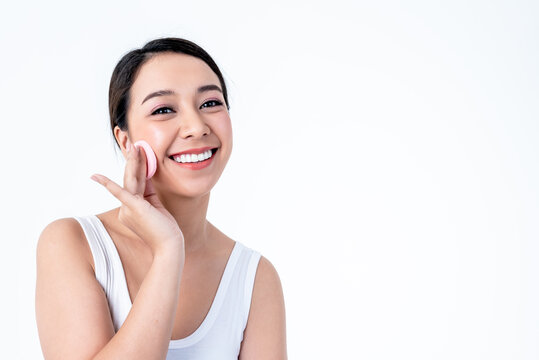 Portrait, Asian pretty young woman is 25 years old She is smiling brightly, She has beautiful white and clean teeth and using puff to touch the face On white background to cosmetic and beauty concept.