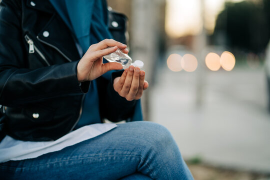 Crop unrecognizable Muslim female in hijab applying antibacterial sanitizer on hands in city street during coronavirus pandemic