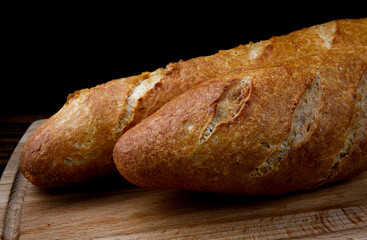 Two French baguettes on a cutting board.