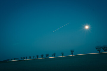 Voiture qui traverse un champ sous la lune
