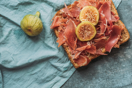 Delicious toast of Iberico ham, cheese and fresh figs on the blue tablecloth, Delicious appetizer, ideal as an aperitif. Healthy food