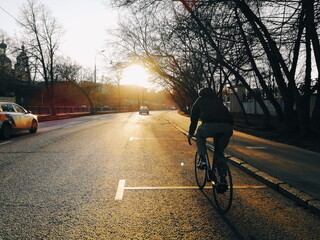 cyclist rides through the city at sunset