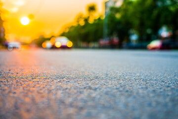 Sunset in the city, the cars driving on the road. Close up view from the asphalt level