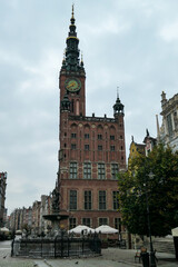 The Neptune's Fountain in Old Town of Gdansk, Poland. The fountain is located in the central point. Red bricked Town Hall building in the back. City tour. A bit of overcast