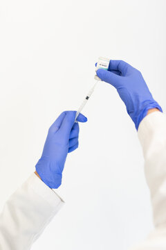 Cropped unrecognizable doctor in latex gloves filling in syringe from bottle with vaccine preparing to vaccinate patient in clinic during coronavirus outbreak