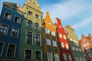 A close up of the facades of tall building in the middle of Old Town in Gdansk, Poland. The buildings have many bright colors, they are richly decorated. City tour. Clear day.