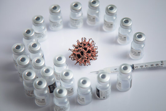 Microscopic Simulation Of COVID-19 Virus Pattern In Background Surrounded By Vaccine Vials