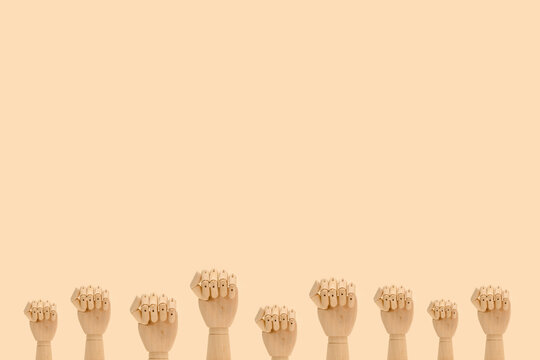 Minimalistic composition of wooden hands demonstrating fists as symbol of protest placed against beige background