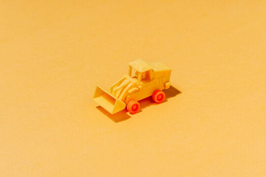 High angle collection of similar tractor toys symmetrical arranged on yellow surface as abstract background