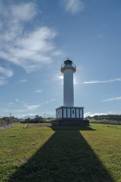 Shadow leading to white lighthouse placed in Faro de Lastres in Asturias in Spain under cloudless blue sky in daytime