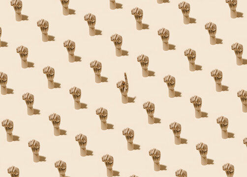 From above of pattern of wooden hands with clenched fists and one with index finger pointing up on beige background