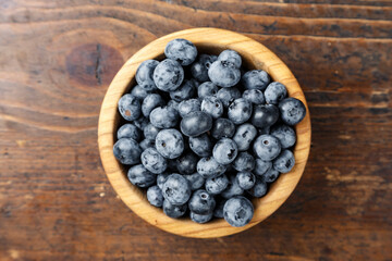 Freshly picked blueberries in wooden bowl on wooden background.  Concept of healthy and dieting eating.