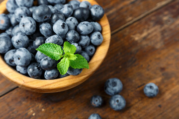 Freshly picked blueberries in wooden bowl on wooden background.  Concept of healthy and dieting eating.