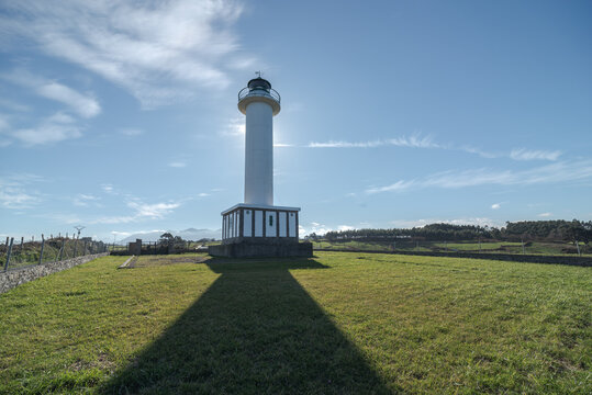 Shadow leading to white lighthouse placed in Faro de Lastres in Asturias in Spain under cloudless blue sky in daytime