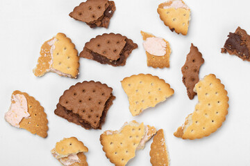 Pieces of chocolate chip cookies and biscuits with filling on a white plate close-up. Top view.
