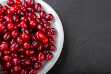 Dogwood berries in a white plate on a black board.