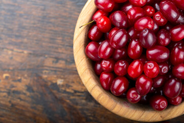 Dogwood in a plate on a wooden background. Gathering the summer harvest.