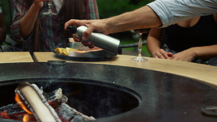 People preparing bbq food cooking outdoors. Man chef hands spraying oil outside
