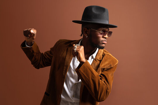 Young African American male in trendy apparel and hat dancing looking away