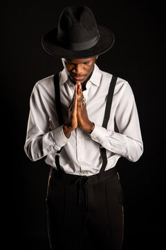 Young unshaven African American male in white shirt and rings on fingers with prayer hands