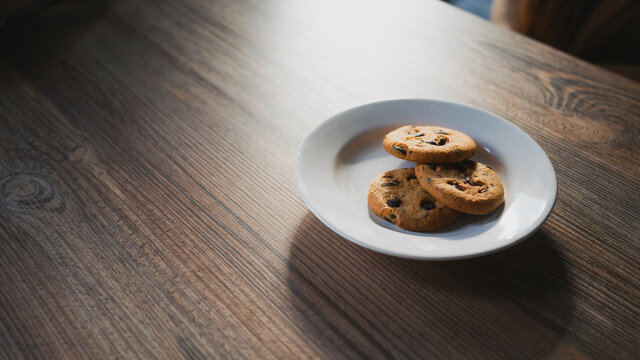 From above of plate with tasty oatmeal biscuits with chocolate chips on wooden table