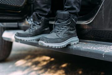 Anonymous man and crop of feet before getting out of an off-road car