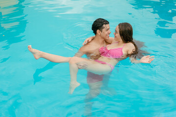 couple swimming in the pool on a sunny day, couple is on vacation swimming in the pool