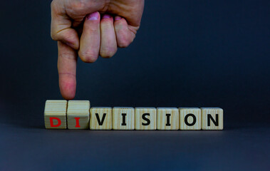 Division or vision symbol. Businessman turns wooden cubes and changes the word 'division' to 'vision'. Beautiful grey table, grey background. Business, division or vision concept. Copy space.