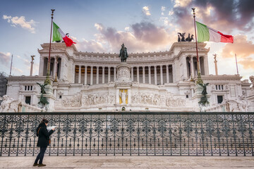 Low angle of female tourist standing with map near Altar of the Fatherland with Victor Emmanuel II National Monument during vacation in Rome