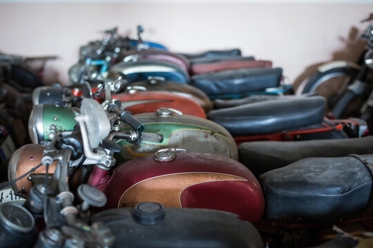 Many old fashioned damaged rusty motorcycles placed in rows in repair service workshop