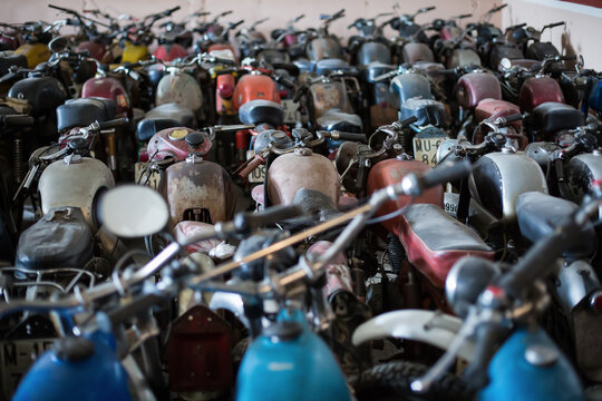 Many old fashioned damaged rusty motorcycles placed in rows in repair service workshop