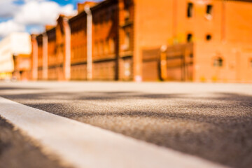 Fototapeta premium Summer in the city, the empty street with the building of red brick. Close up view from the level of the dividing line