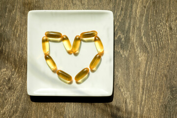 Bright yellow pills on a plate in a form of a heart. Medical concept.