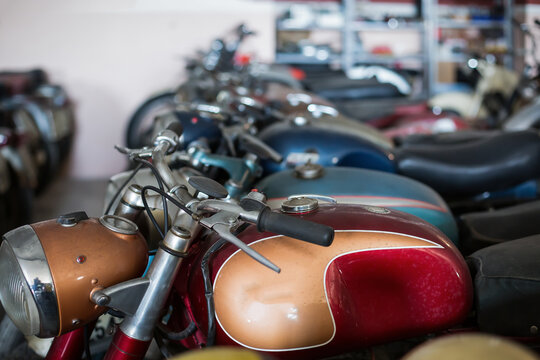 Many old fashioned damaged rusty motorcycles placed in rows in repair service workshop