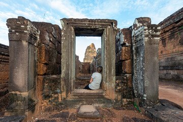 Back view of anonymous female traveler contemplating old Angkor Wat with weathered columns in Cambodia